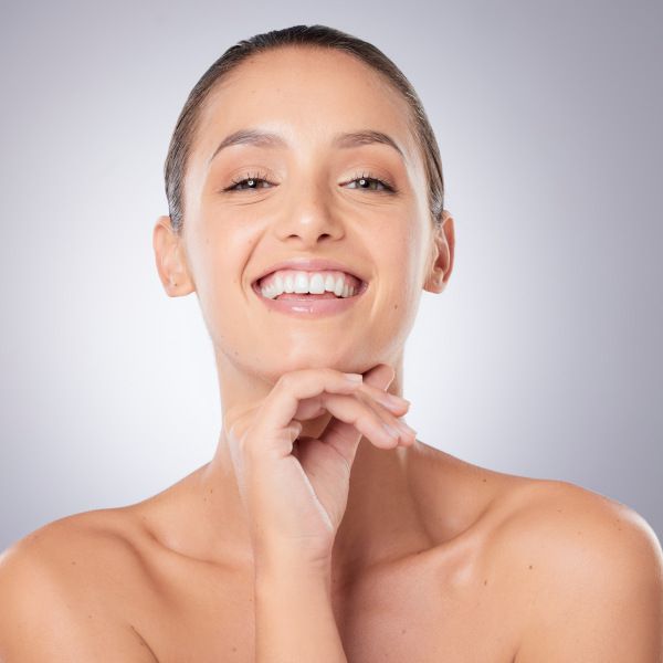 Vista frontal de una chica sonriendo con el rostro cuidado.